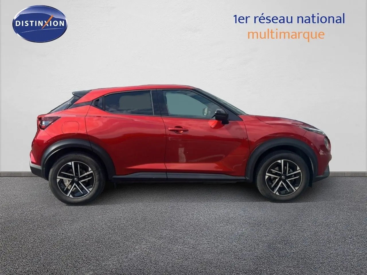 Profil côté gauche d'un Nissan Juke 2024 rouge Fuji Metal avec jantes alliage noires et toit noir.