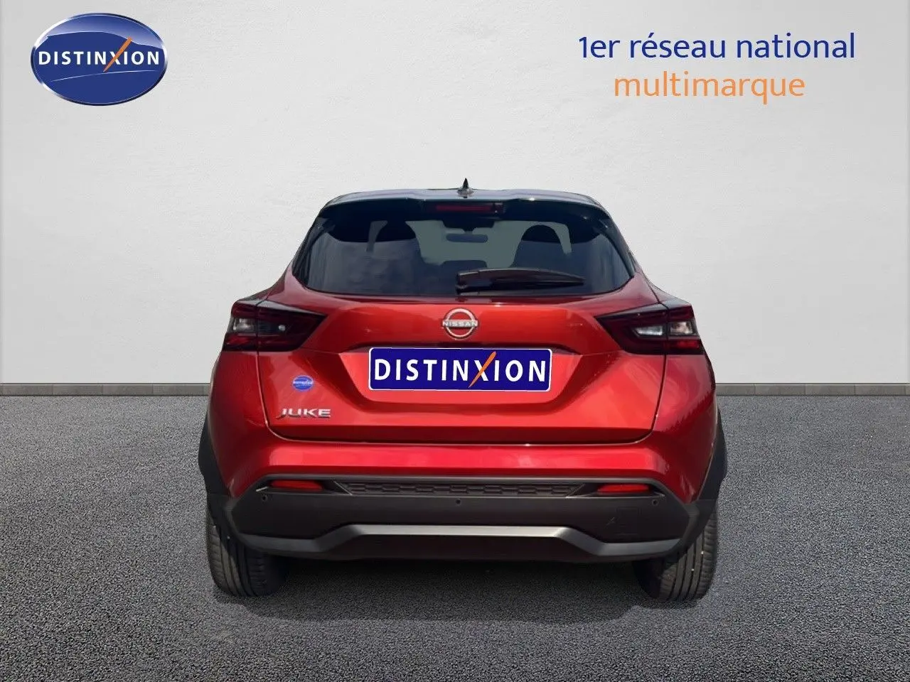 Vue arrière d'un Nissan Juke 2024 rouge Fuji Metal avec toit noir et feux arrière LED distinctifs.