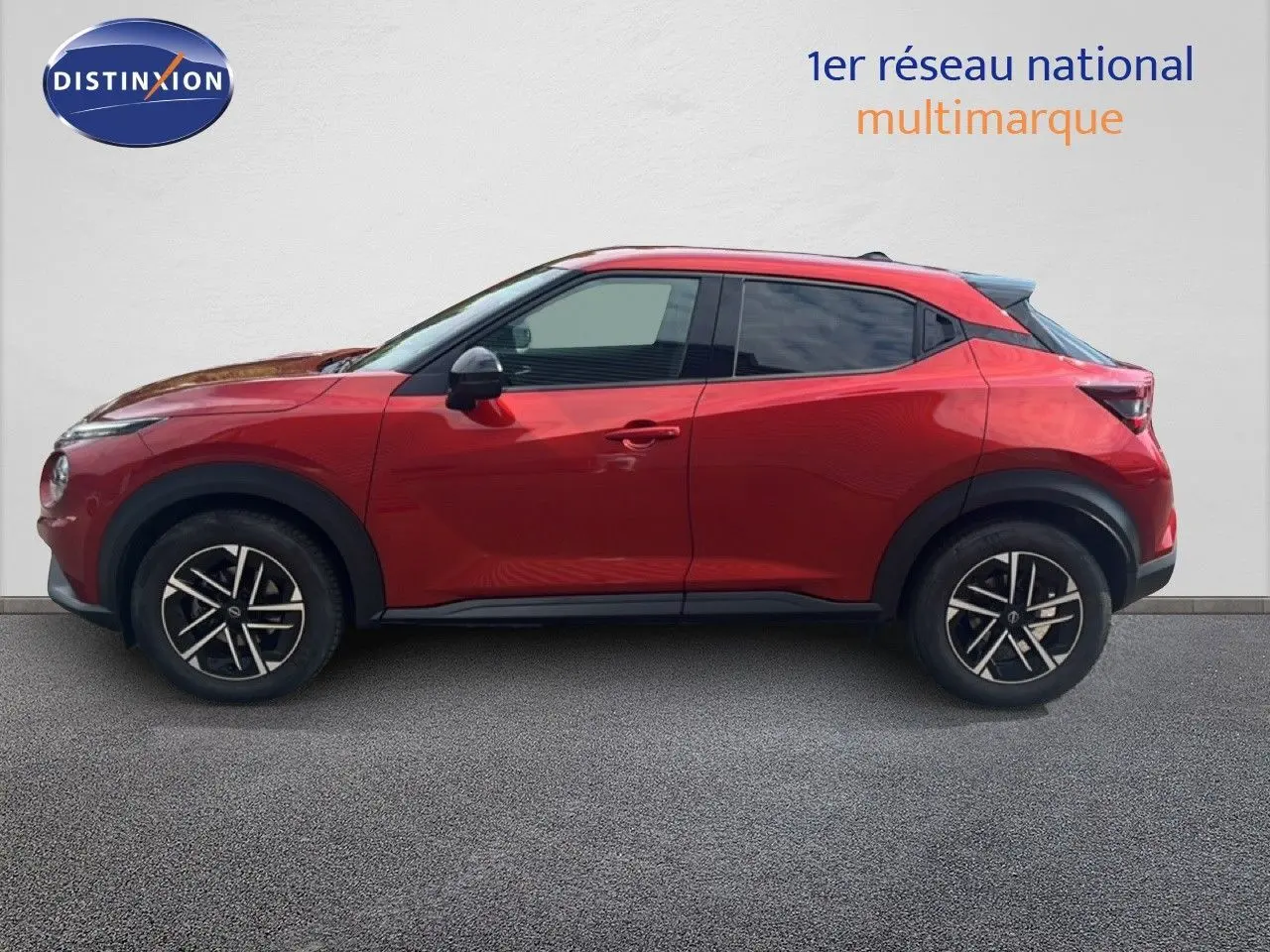 Profil droit d'un Nissan Juke 2024 rouge Fuji Metal avec jantes alliage noires et toit noir contrasté.