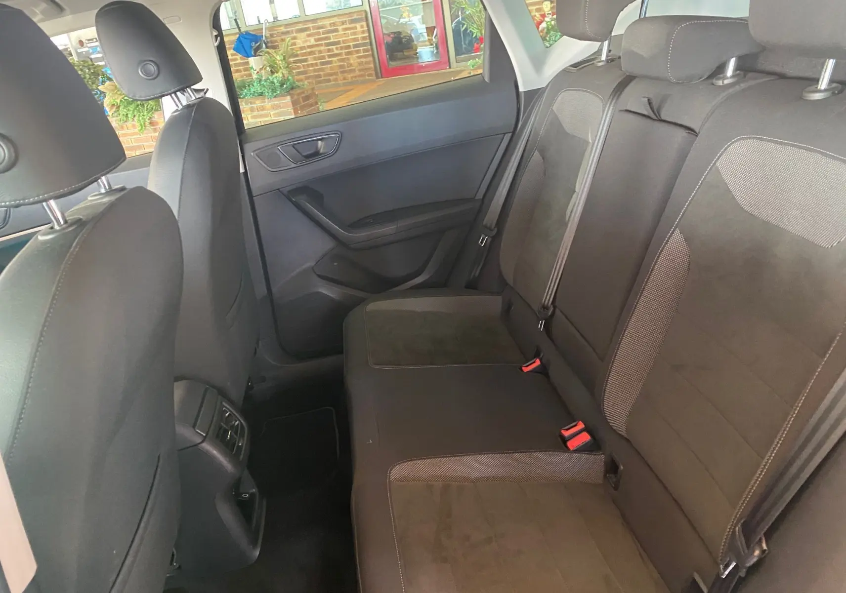 Vue intérieure arrière côté droit du SEAT Ateca Urban 2019 noir, montrant les sièges en tissu noir avec appuie-têtes et ceintures de sécurité.