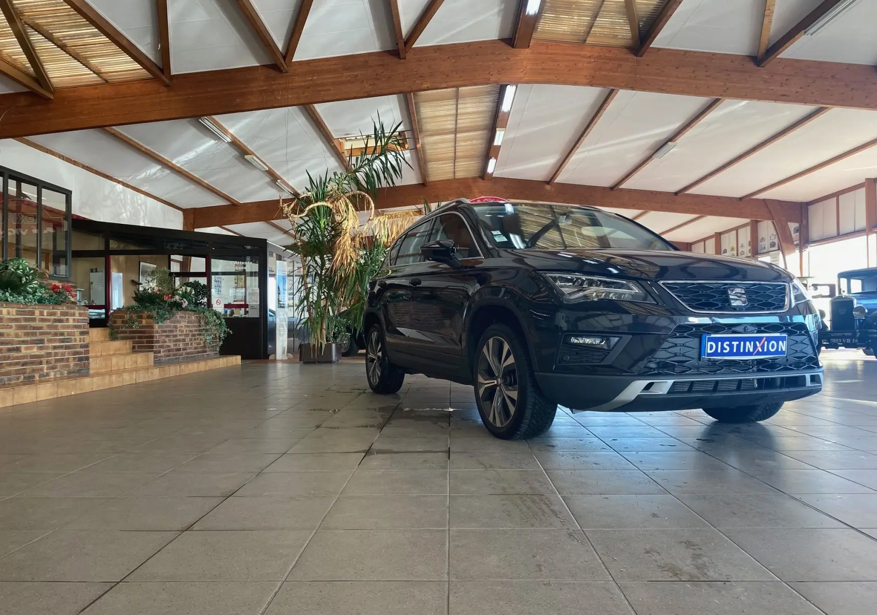 SEAT Ateca Urban noir vue 3/4 avant droit dans un showroom lumineux avec plafond en bois apparent.