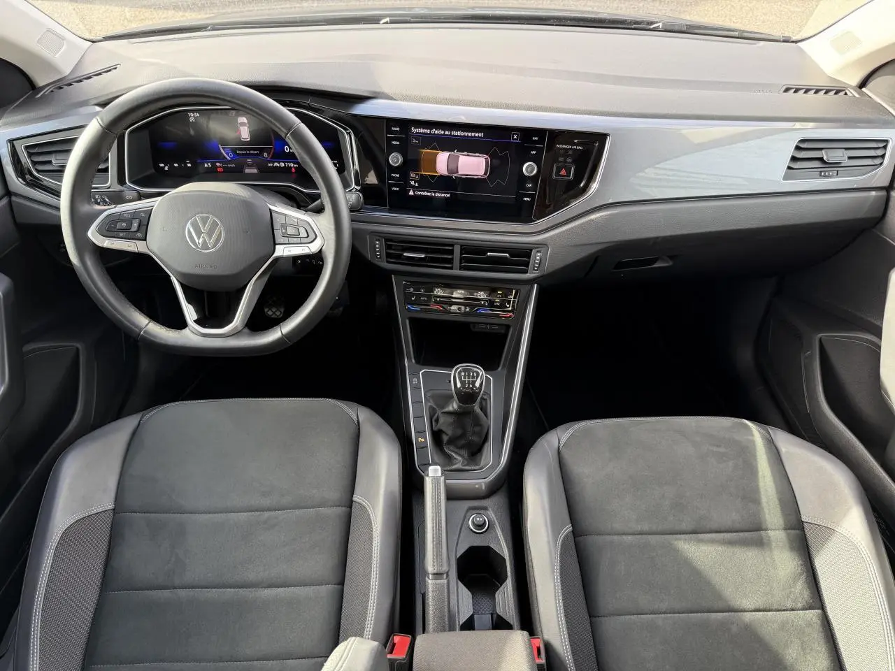 Vue intérieure frontale du tableau de bord et des sièges sport noirs de la Volkswagen Polo 1.0 TSI 2025 avec boîte manuelle.