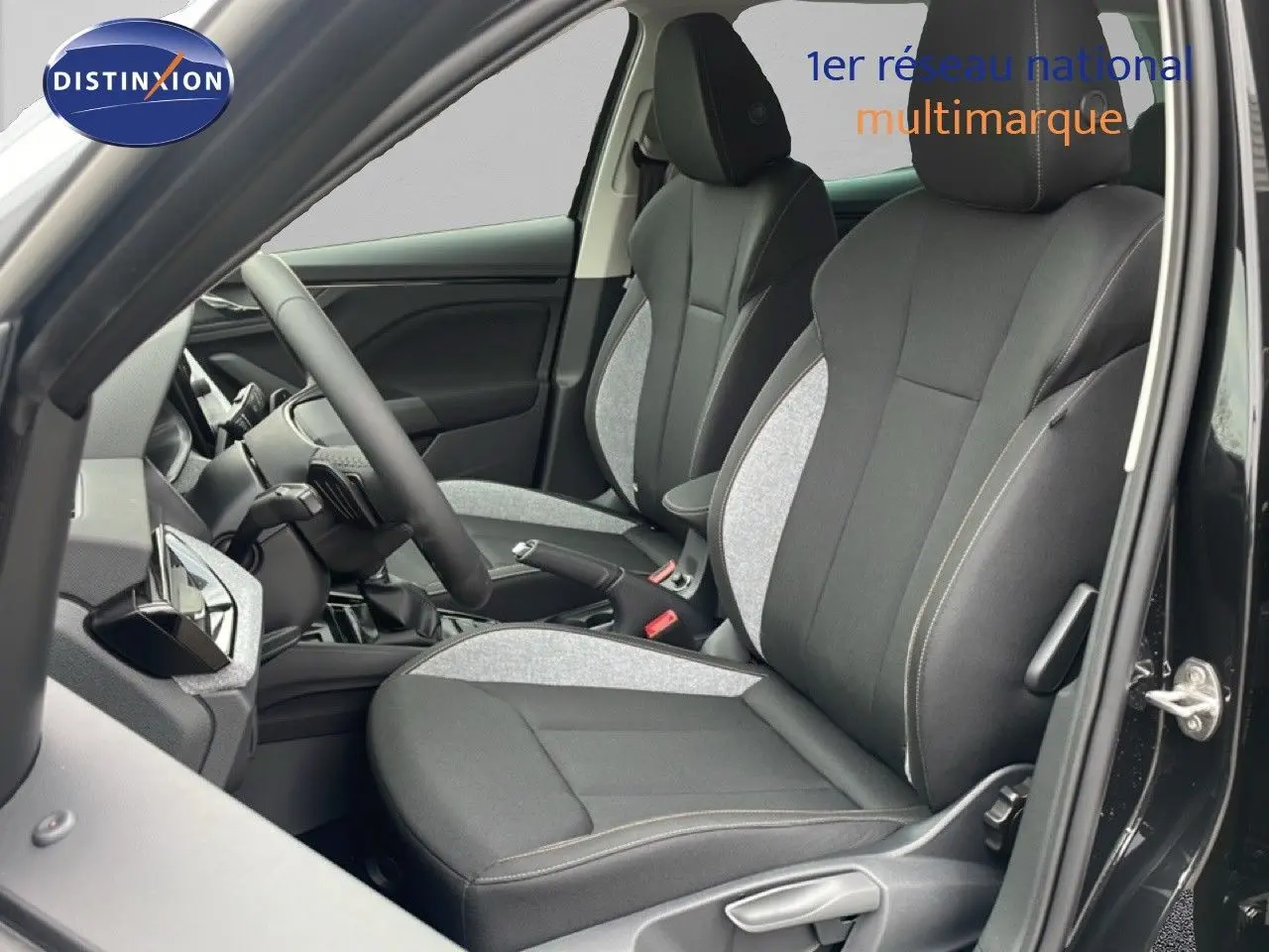 Vue intérieure côté conducteur du Skoda Kamiq 2025 noir, mettant en valeur les sièges tissu bicolores gris et noir avec coutures contrastées.