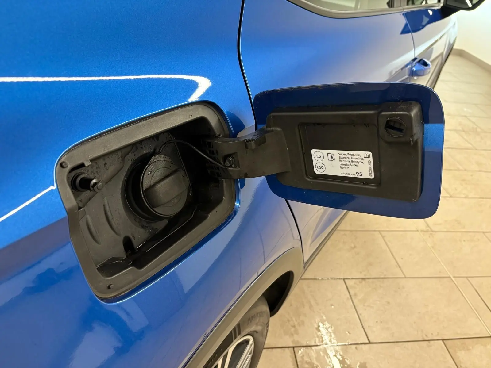 Vue rapprochée de la trappe à carburant ouverte côté gauche d’un SEAT Arona bleu saphir avec toit noir.