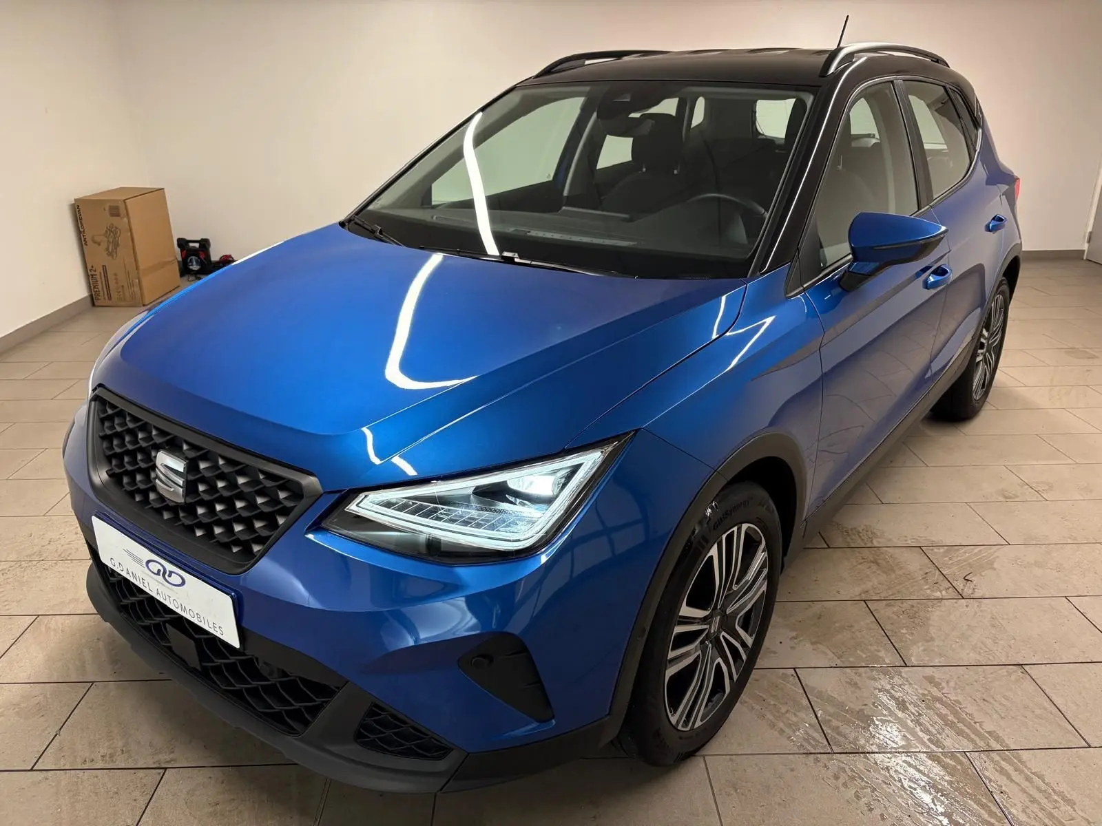 SEAT Arona bleu saphir avec toit noir, vue 3/4 avant droit mettant en valeur les phares LED et la calandre noire.