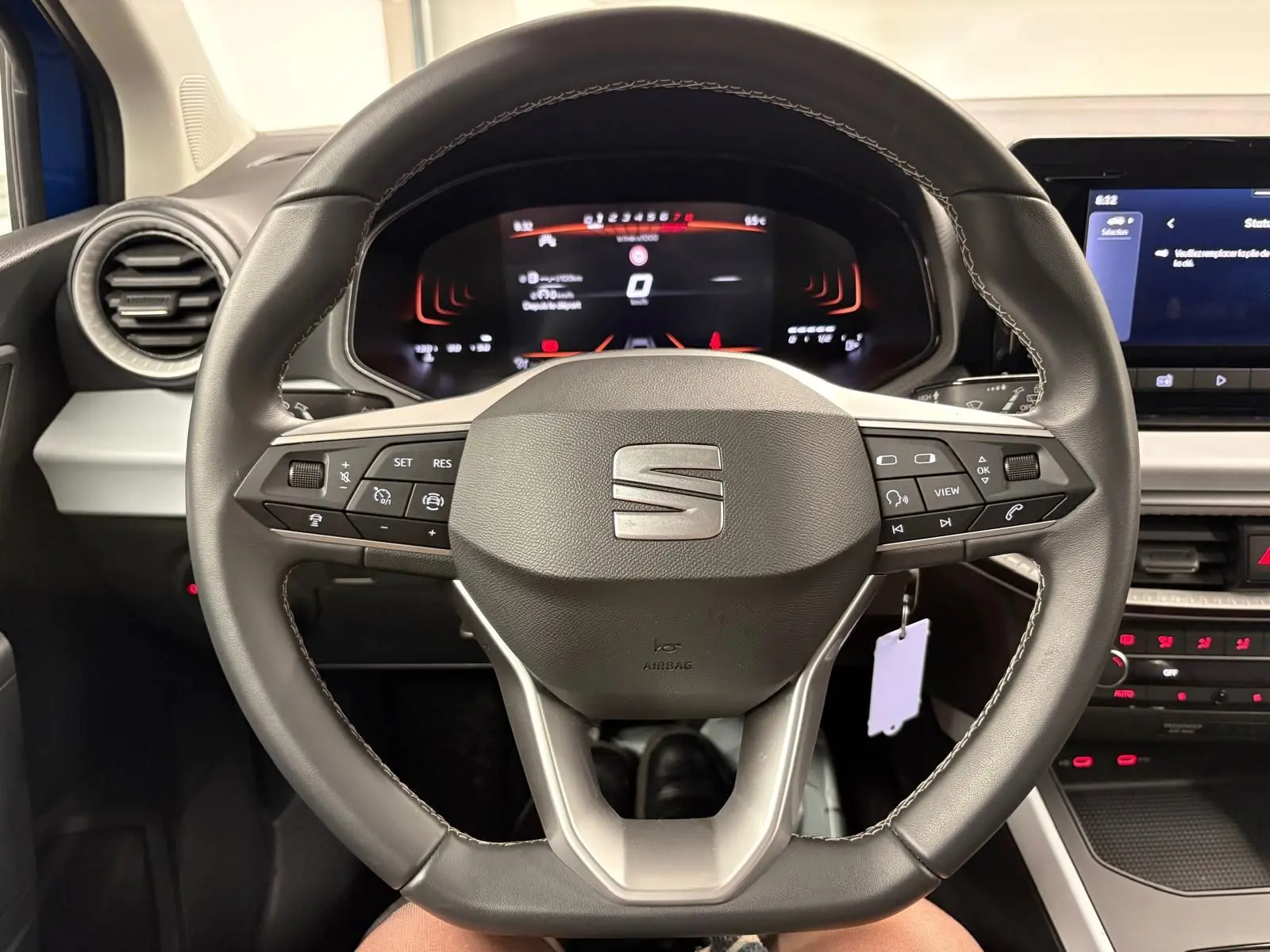 Vue rapprochée du volant multifonction noir du SEAT Arona 2025 avec tableau de bord numérique en arrière-plan.