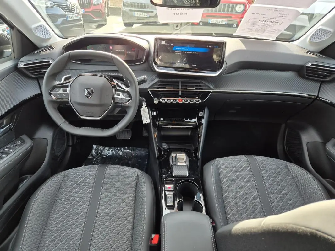 Vue intérieure avant du Peugeot 208 Hybrid 110 e-DCS6 Allure 2025, avec volant compact, écran tactile et sièges gris.
