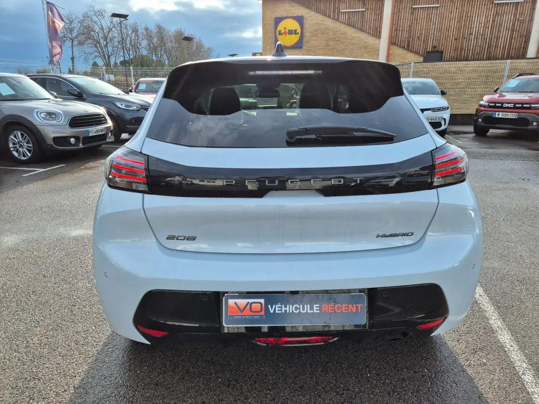 Vue arrière d'une Peugeot 208 Hybrid blanche 2025 avec feux LED et logo Peugeot noir brillant.