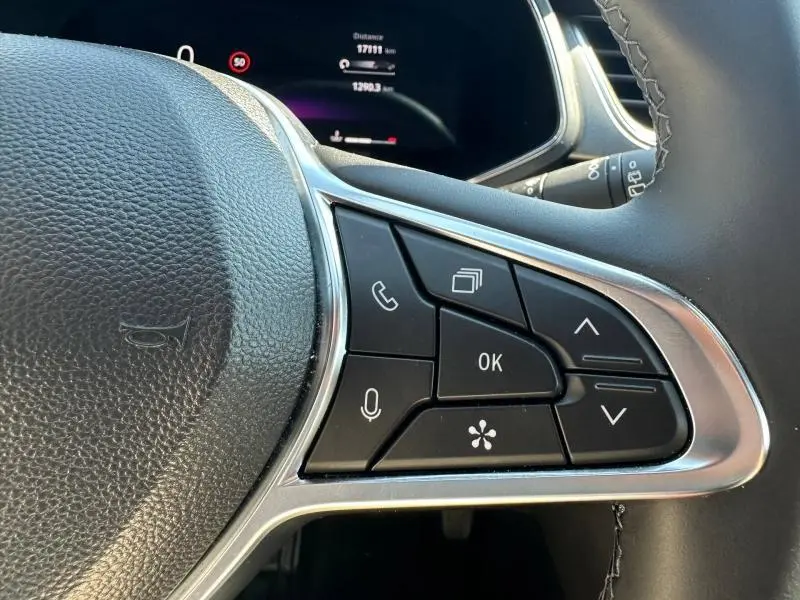 Gros plan sur les commandes multifonctions à droite du volant noir du Renault Captur 2025, avec écran de tableau de bord en arrière-plan.