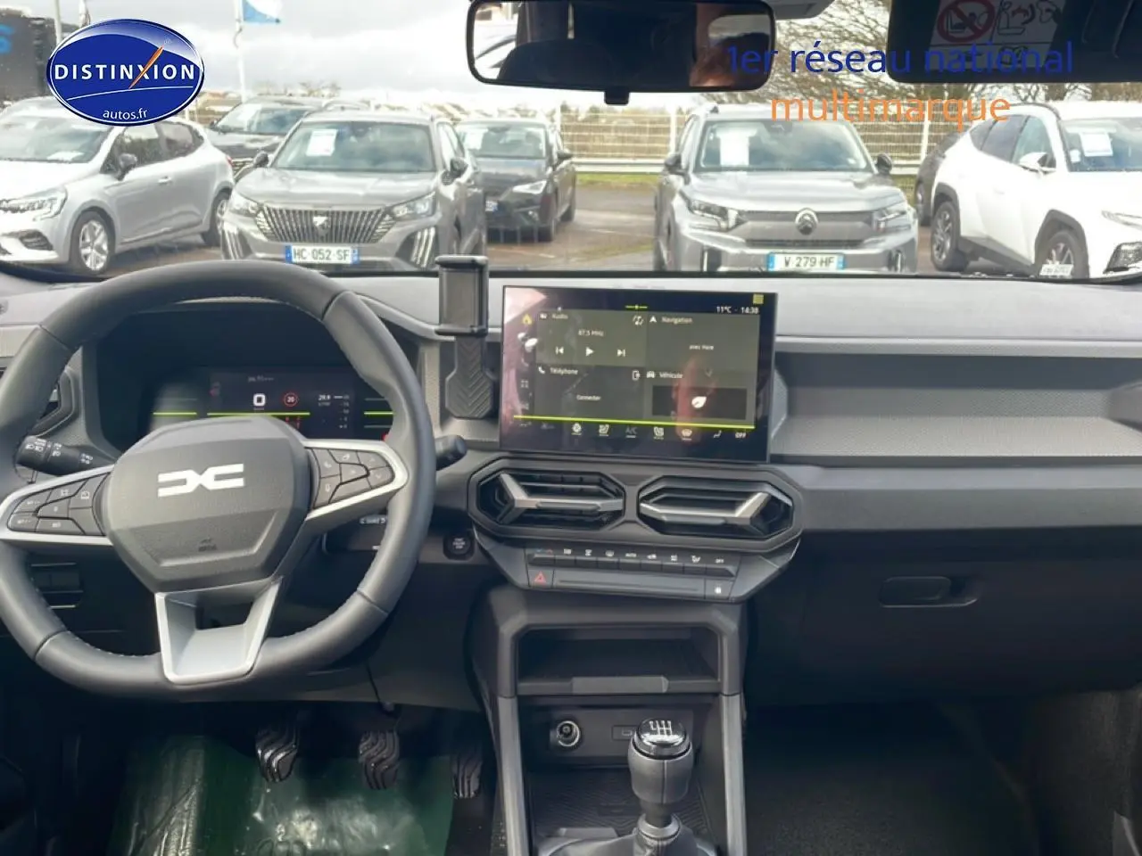 Vue intérieure du tableau de bord et volant du Dacia Duster 1.2 mild hybrid 140 Journey avec écran tactile et boîte manuelle.
