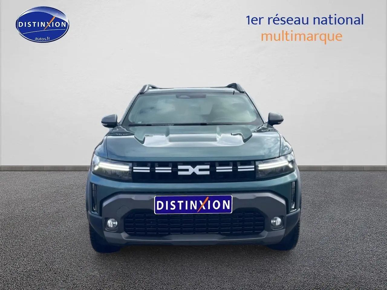 Vue avant du Dacia Duster 1.2 mild hybrid 140 Journey vert cèdre avec calandre distinctive et phares LED allumés.