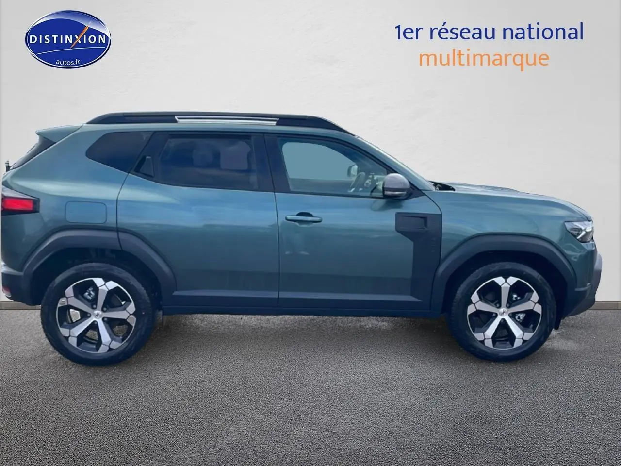 Profil droit du Dacia Duster 2026 vert cèdre avec jantes alliage et barres de toit noires.