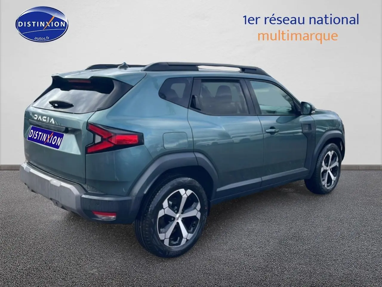 Vue 3/4 arrière droite du Dacia Duster 2026 vert cèdre avec jantes alu et barres de toit visibles.