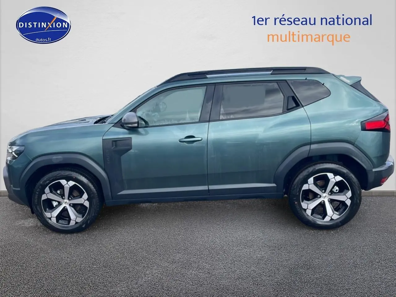 Profil droit du Dacia Duster 2026 vert cèdre avec jantes alliage et barres de toit noires.