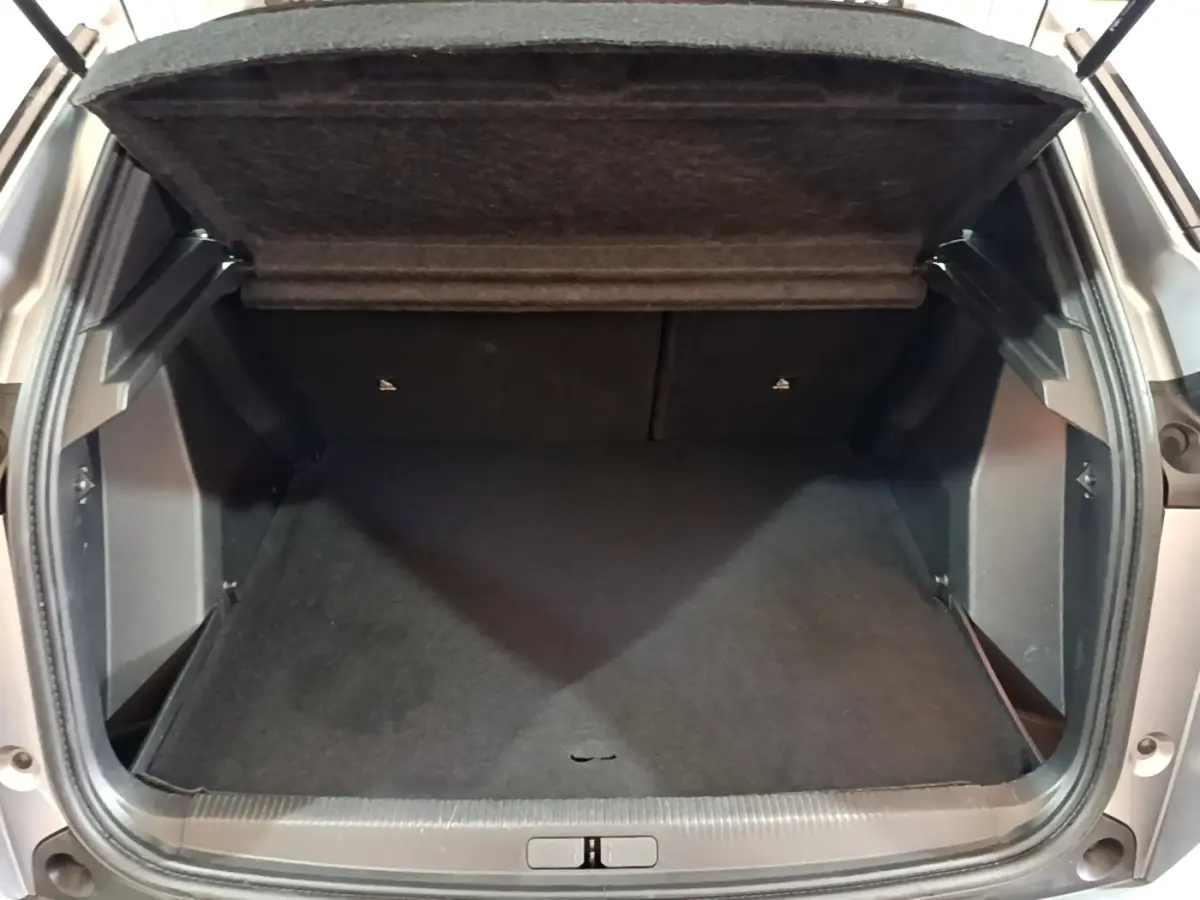 Coffre ouvert vu de face d’un Peugeot 2008 gris clair, montrant l’espace de chargement vide et la tablette arrière relevée.