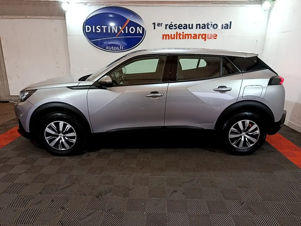 Profil droit d'un Peugeot 2008 gris clair 2021 garé en intérieur avec jantes alliage et toit noir contrasté.