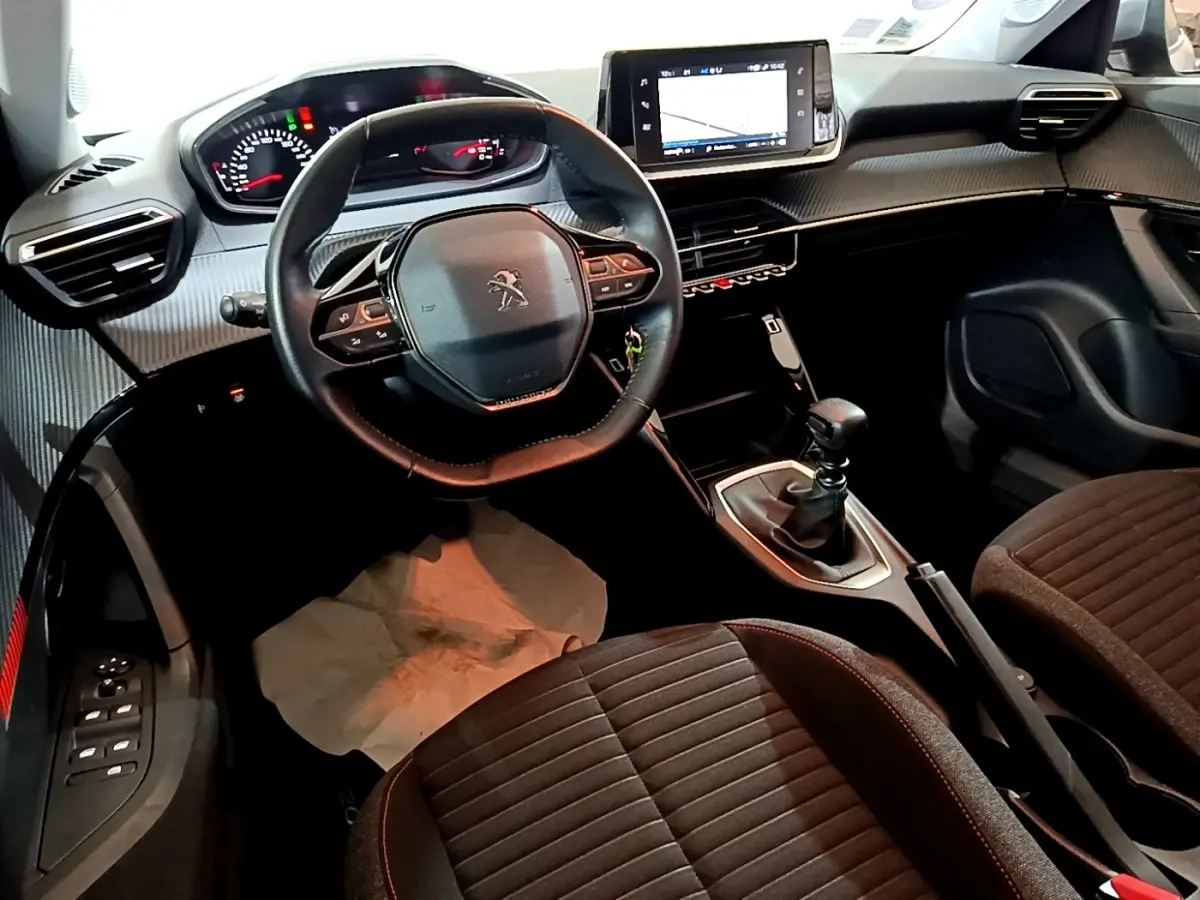 Vue intérieure avant du Peugeot 2008 gris clair, mettant en valeur le volant cuir multifonctions et l’écran tactile central.