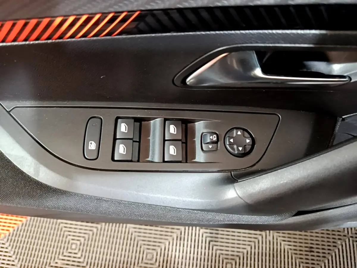 Vue rapprochée du panneau de commande des vitres et rétroviseurs côté conducteur d’un Peugeot 2008 gris clair.