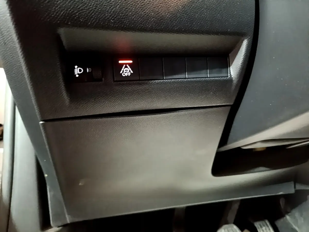 Vue rapprochée des commandes situées sous le tableau de bord côté conducteur du Peugeot 2008 gris clair 2021.