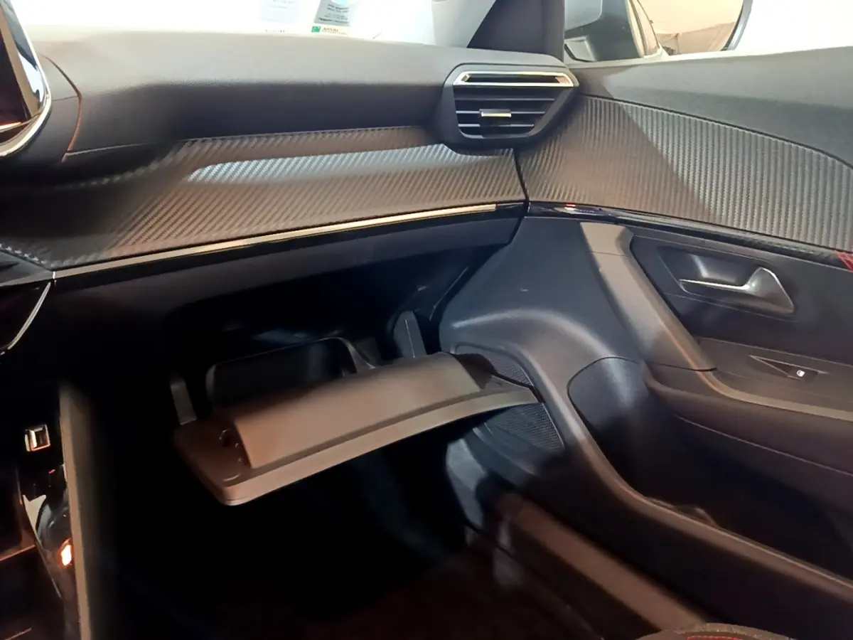 Intérieur du côté passager du Peugeot 2008 2021, tableau de bord avec finition carbone et boîte à gants ouverte.