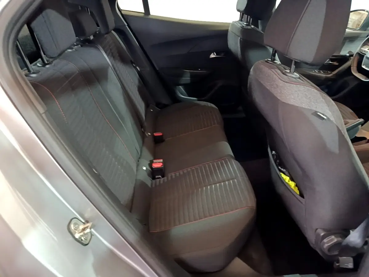 Vue intérieure côté gauche des sièges arrière noirs avec surpiqûres rouges dans un Peugeot 2008 gris clair de 2021.