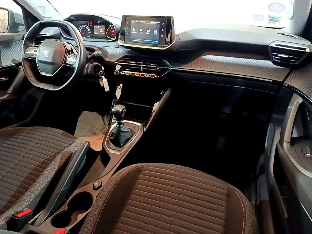 Vue intérieure avant du Peugeot 2008 gris clair 2021, montrant le volant cuir, écran tactile central et boîte manuelle.