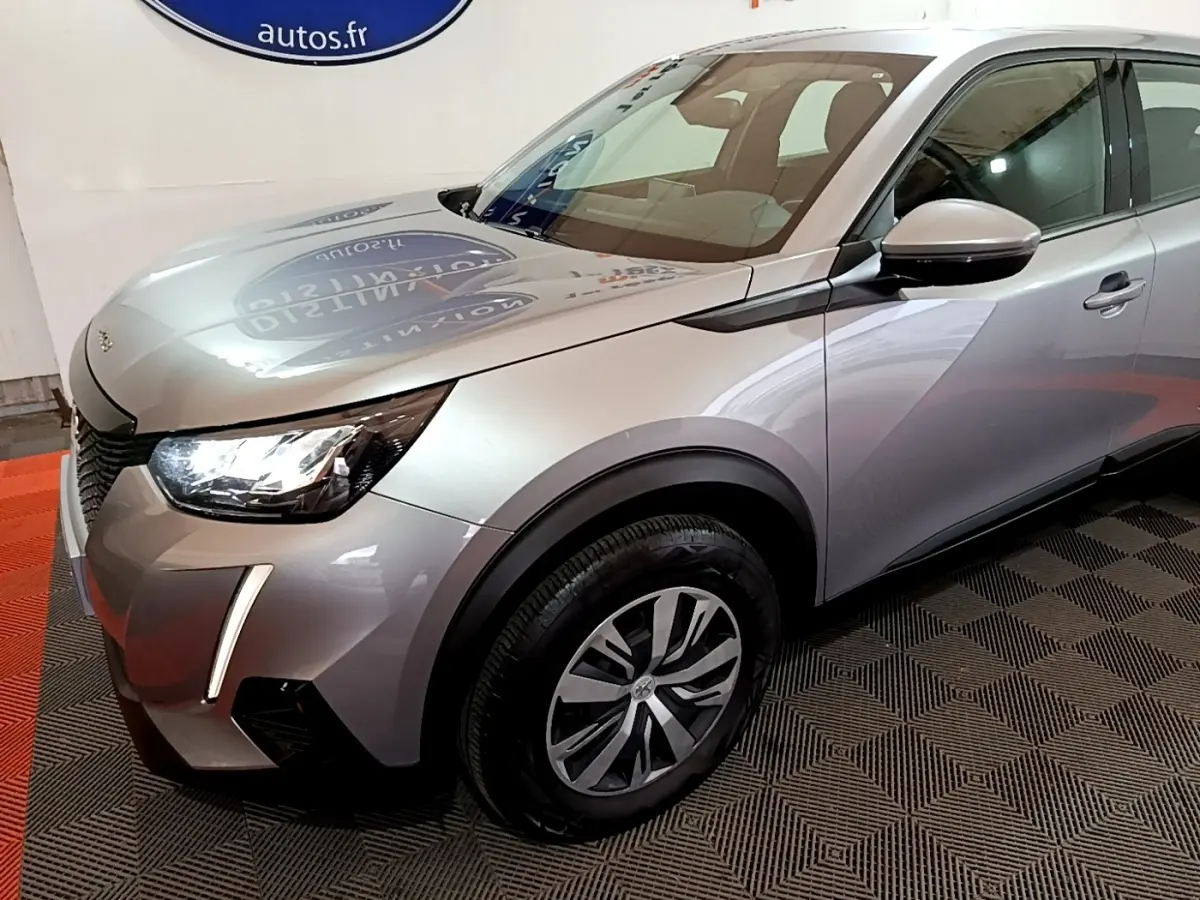 Vue 3/4 avant droit d'un Peugeot 2008 gris clair avec phares LED et jantes alliage distinctives.