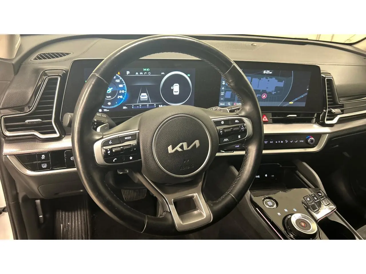 Vue intérieure centrée sur le volant cuir noir et le tableau de bord digital du Kia Sportage hybride 2022.