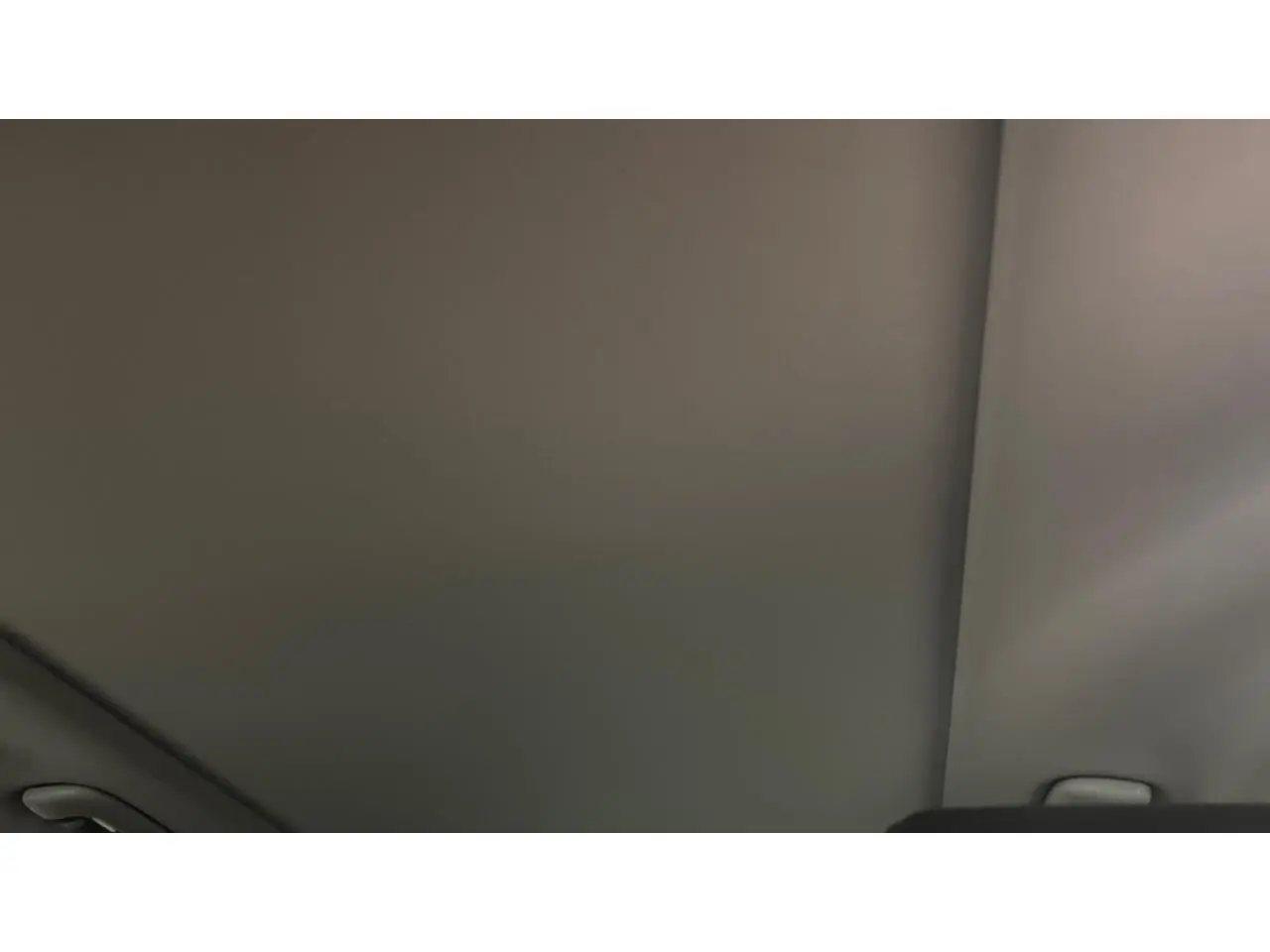 Toit intérieur gris clair du Kia Sportage hybride 2022 avec poignée de maintien visible sur le côté droit