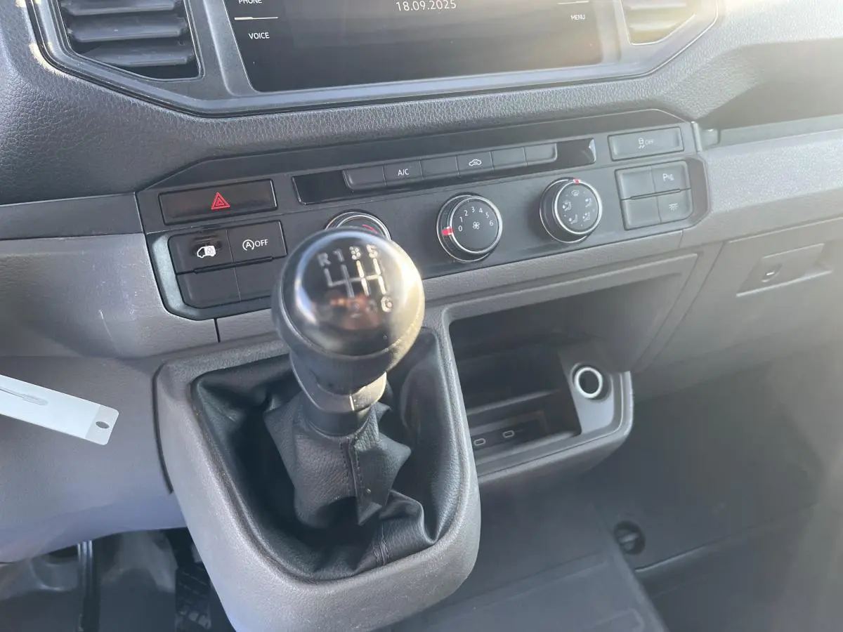 Gros plan sur la commande de boîte manuelle et la console centrale noire du Volkswagen Crafter Fourgon blanc de 2022.