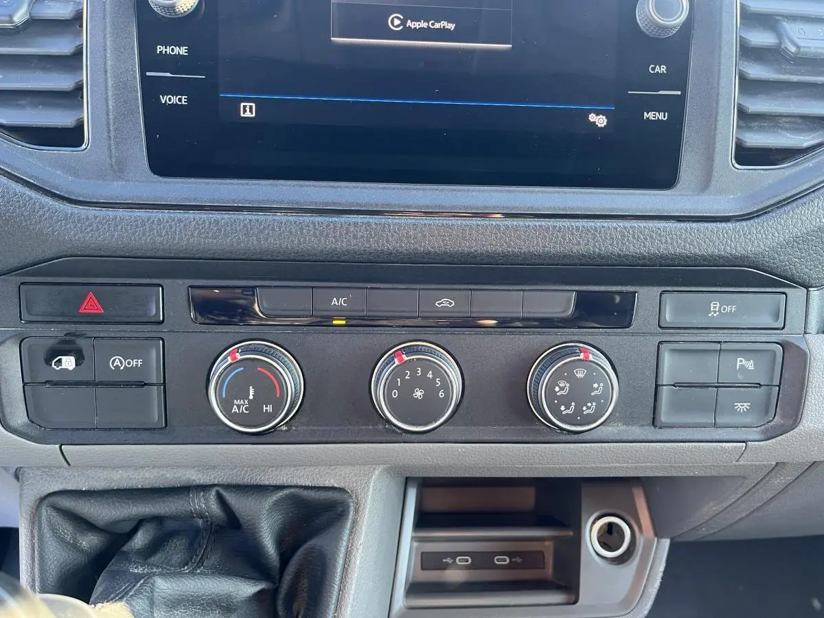 Tableau de bord du Volkswagen Crafter blanc 2022, vue rapprochée des commandes de climatisation et boîte manuelle.