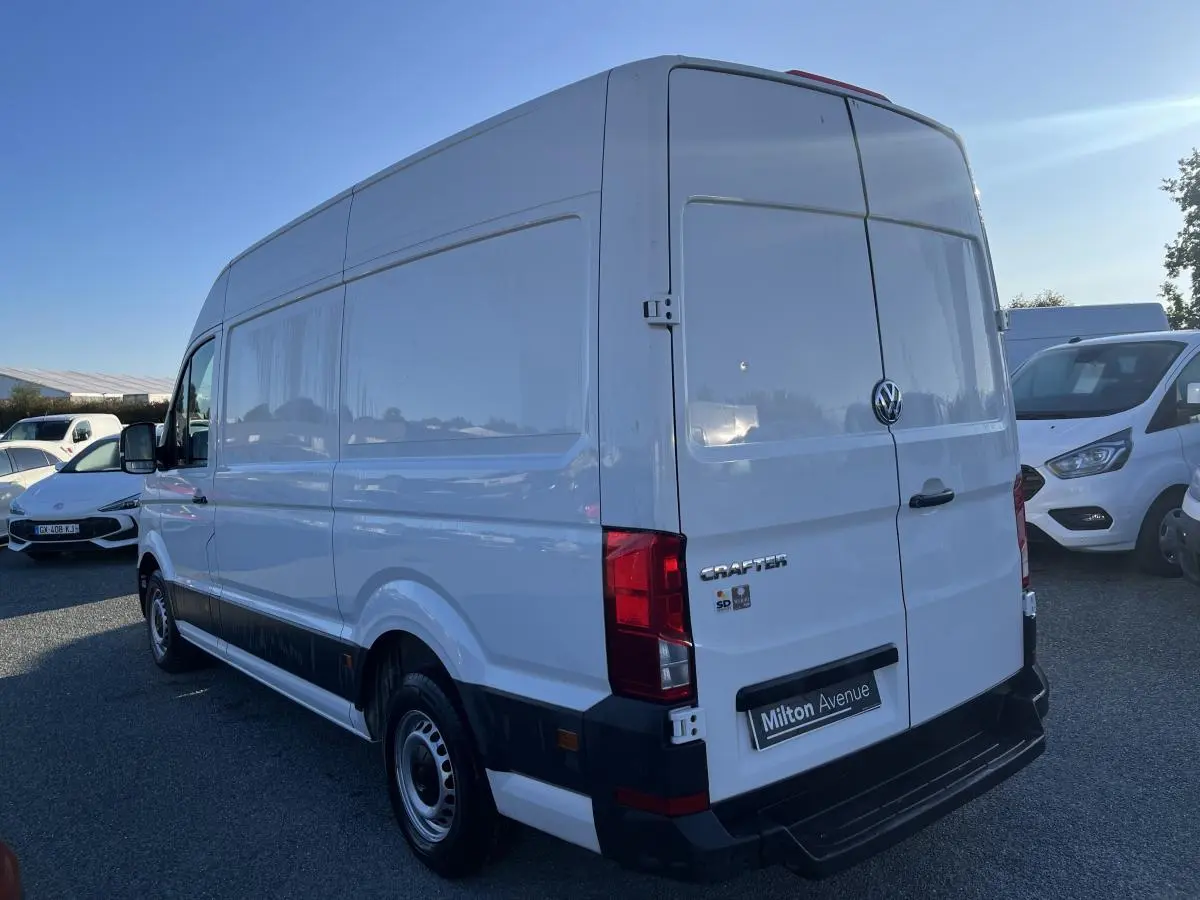 Vue 3/4 arrière droite d'un Volkswagen Crafter fourgon blanc avec portes battantes et jantes acier argentées.
