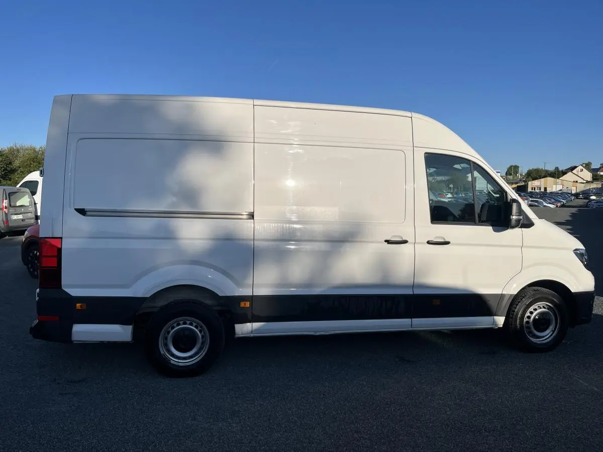 Profil droit d'un Volkswagen Crafter Fourgon blanc avec toit haut, portes latérales coulissantes et jantes acier argentées.