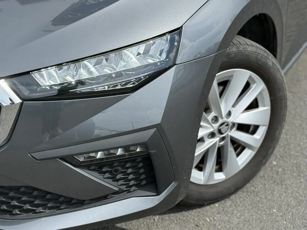 Gros plan sur l'avant droit gris graphite de la Skoda Scala TSI 116, mettant en valeur le phare LED et la jante alliage 16 pouces.