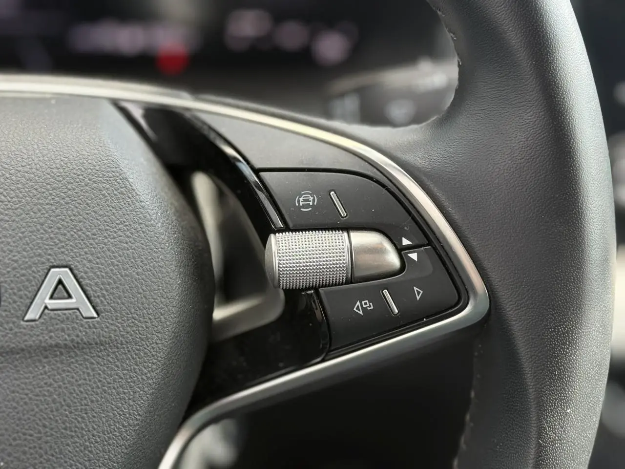 Gros plan sur les commandes à droite du volant en cuir noir de la Skoda Scala TSI 116 gris graphite.