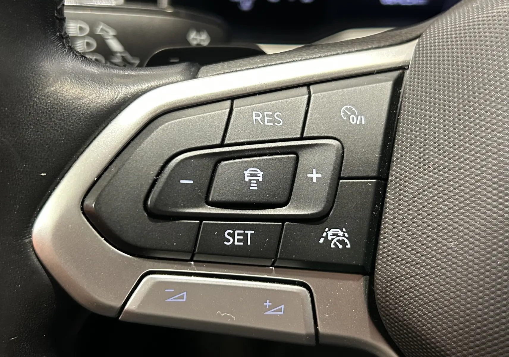 Gros plan sur les commandes de régulateur de vitesse au volant d’un Volkswagen Taigo blanc pur 2022.