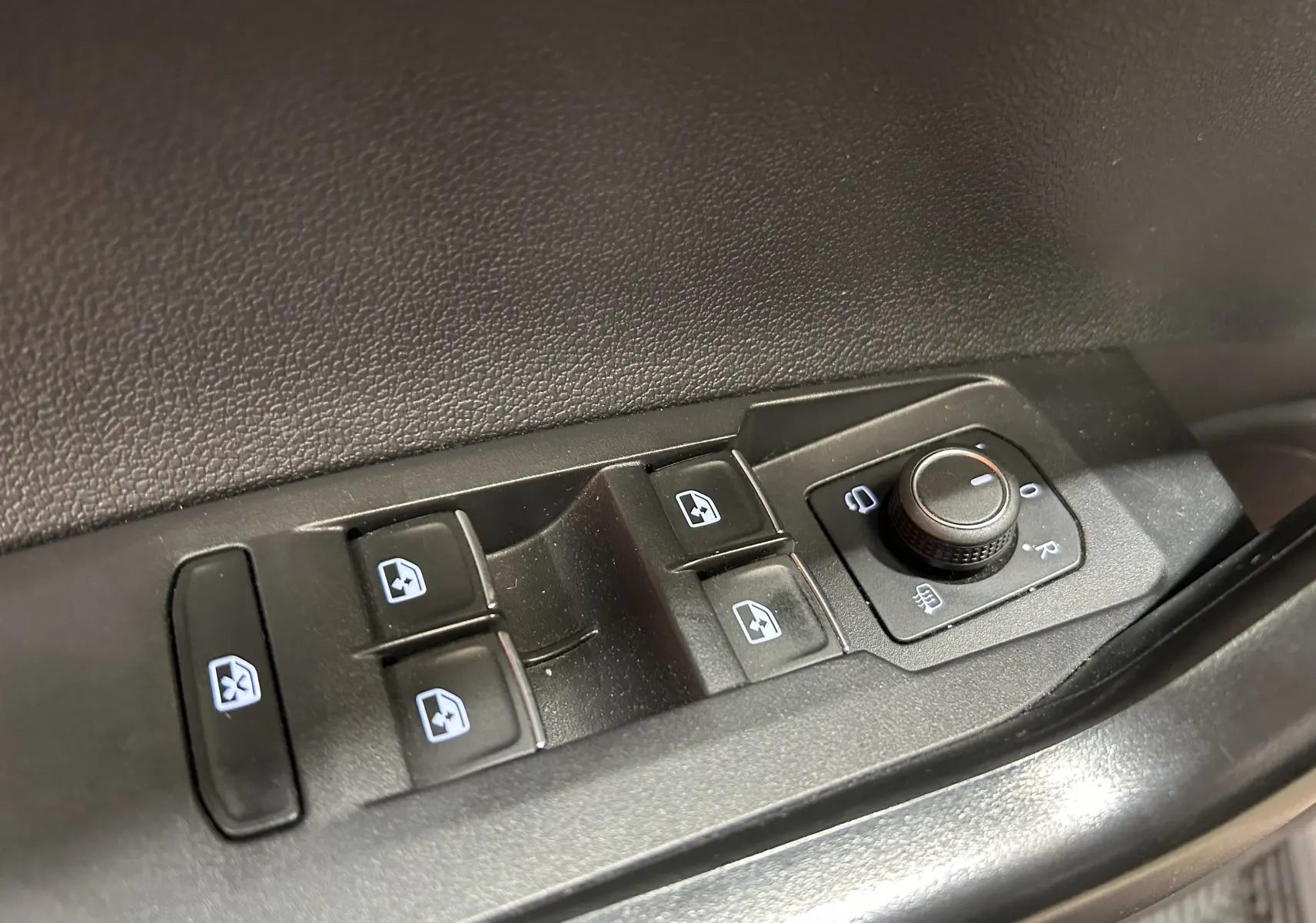 Gros plan sur les commandes de lève-vitres et réglage des rétroviseurs côté conducteur du Volkswagen Taigo blanc 2022.