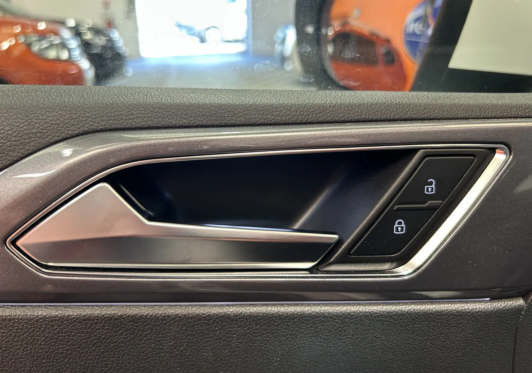 Poignée intérieure côté gauche de la porte d'une Volkswagen Taigo blanche, avec boutons de verrouillage éclairés.