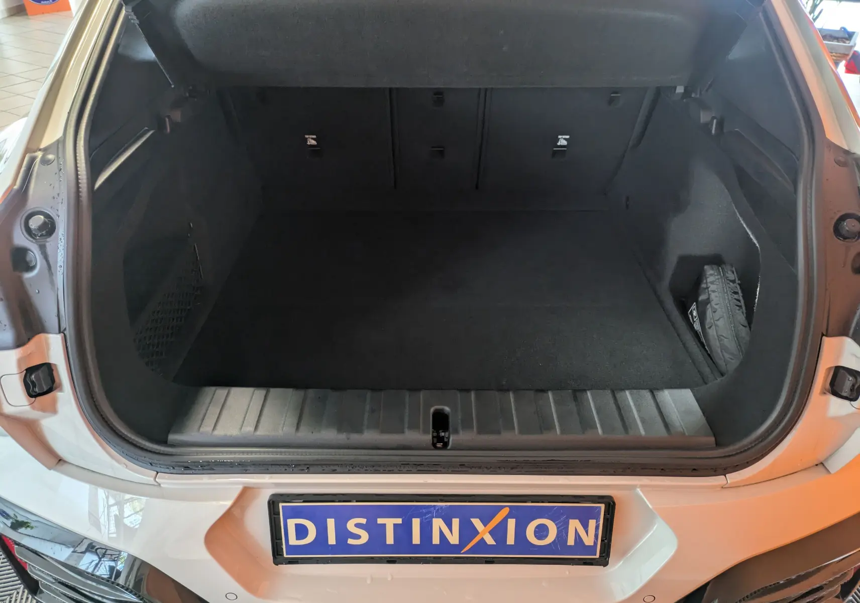 Coffre ouvert vu de l'arrière d'un BMW X2 sDrive blanc alpin, montrant un espace de chargement spacieux et propre.