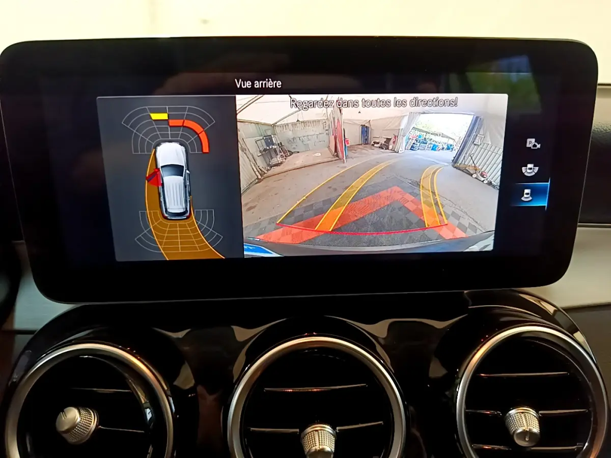Écran tactile intérieur affichant la caméra de recul et les capteurs de stationnement du Mercedes GLC hybride gris foncé.