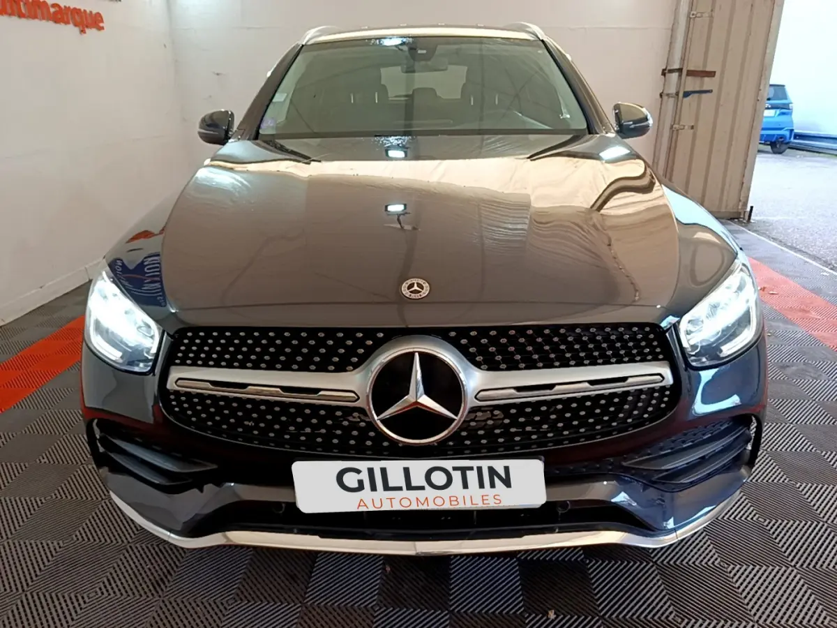 Vue frontale d'un Mercedes GLC 300 E AMG Line gris foncé avec phares LED allumés et calandre distinctive.