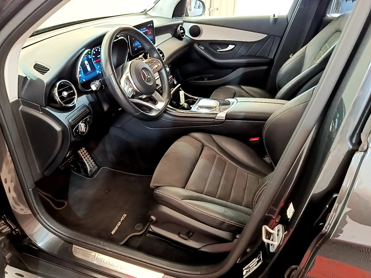 Intérieur côté conducteur du Mercedes GLC 300 E AMG Line 2021 gris foncé, avec volant cuir et tableau de bord numérique.