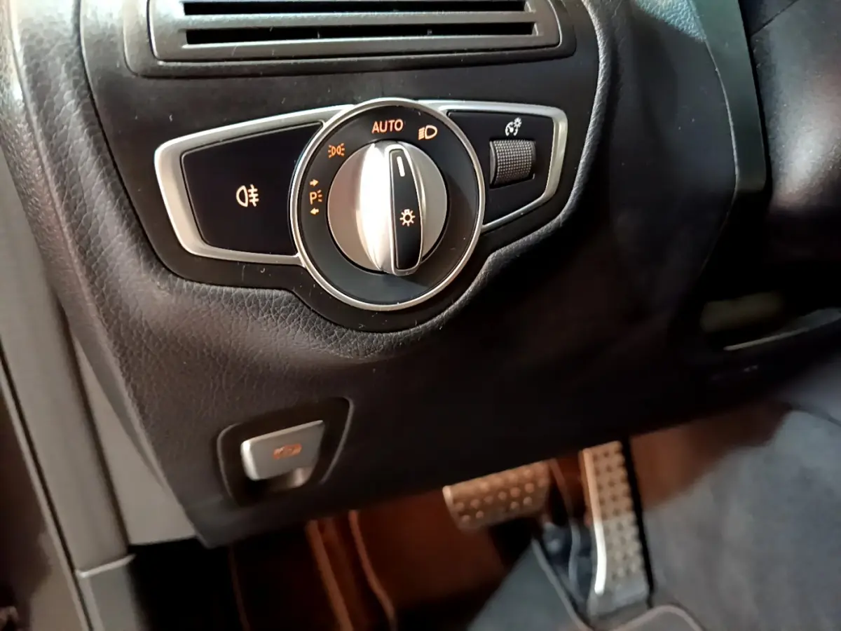 Gros plan sur le bouton de commande des phares dans l'habitacle noir du Mercedes GLC 300 E AMG Line 2021.