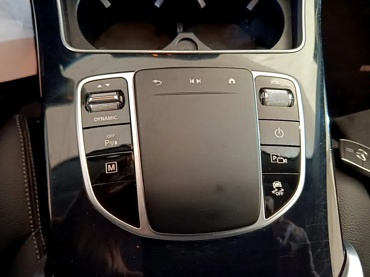 Gros plan sur la console centrale noire brillante du Mercedes GLC 300 E AMG Line avec commandes tactiles et molette volume.