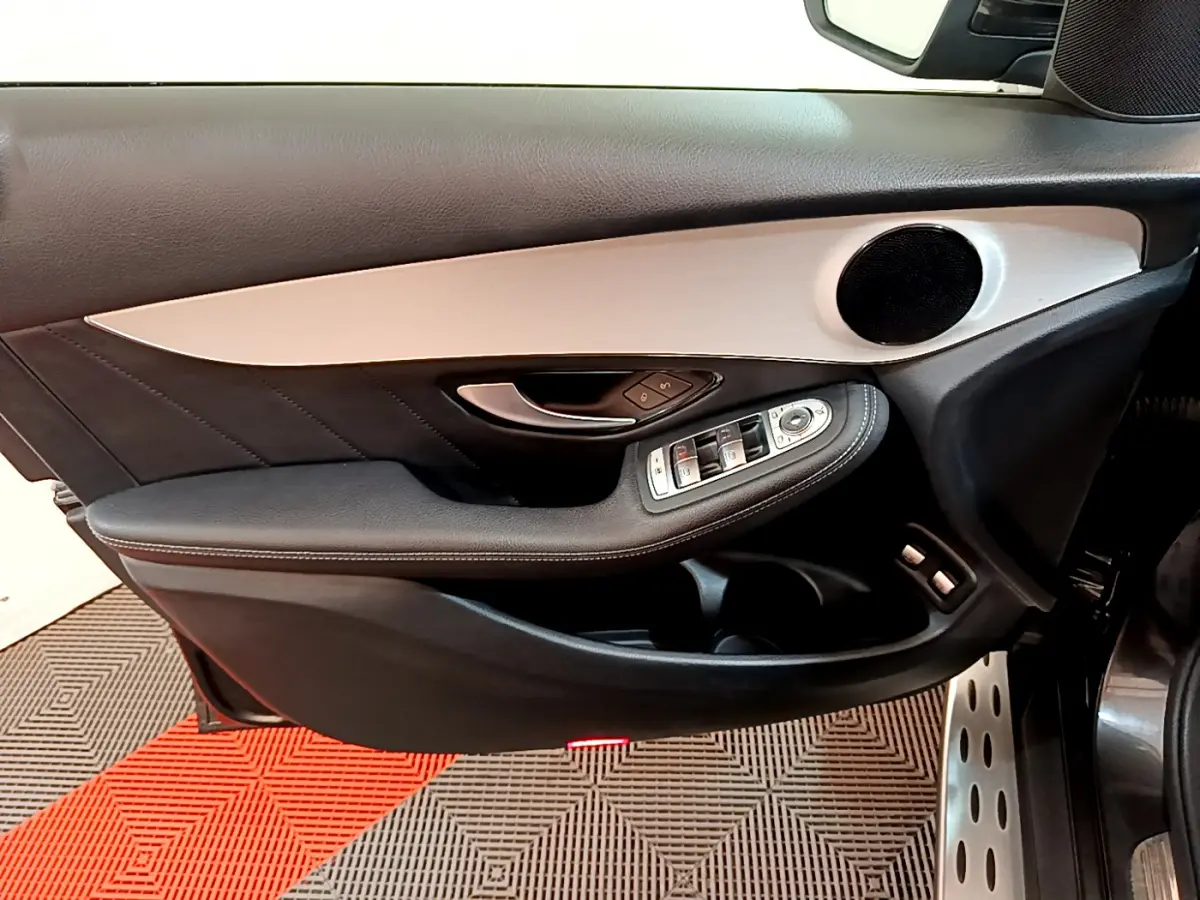 Gros plan sur la porte avant gauche noire et grise du Mercedes GLC 300 E AMG Line avec commandes électriques et haut-parleur rond.