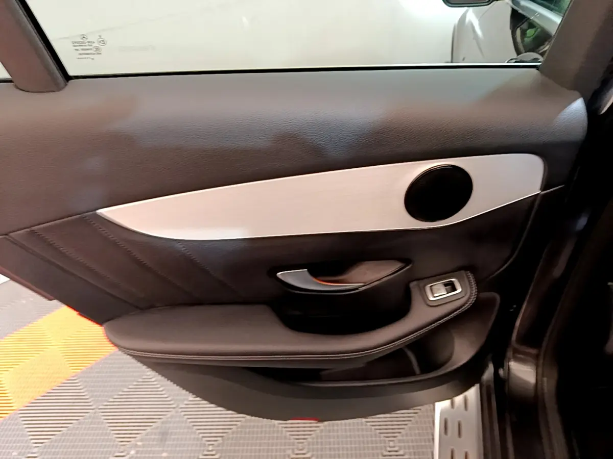 Vue rapprochée de la porte intérieure côté droit du Mercedes GLC 300 E AMG Line gris foncé avec garniture noire et insert argenté.