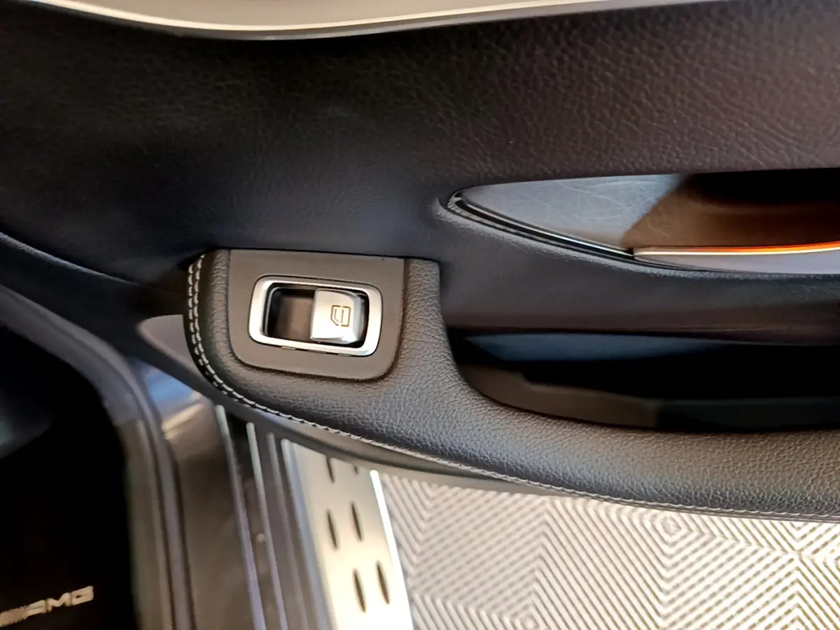 Gros plan sur la poignée intérieure noire avec bouton de lève-vitre du Mercedes GLC 300 E AMG Line gris foncé.