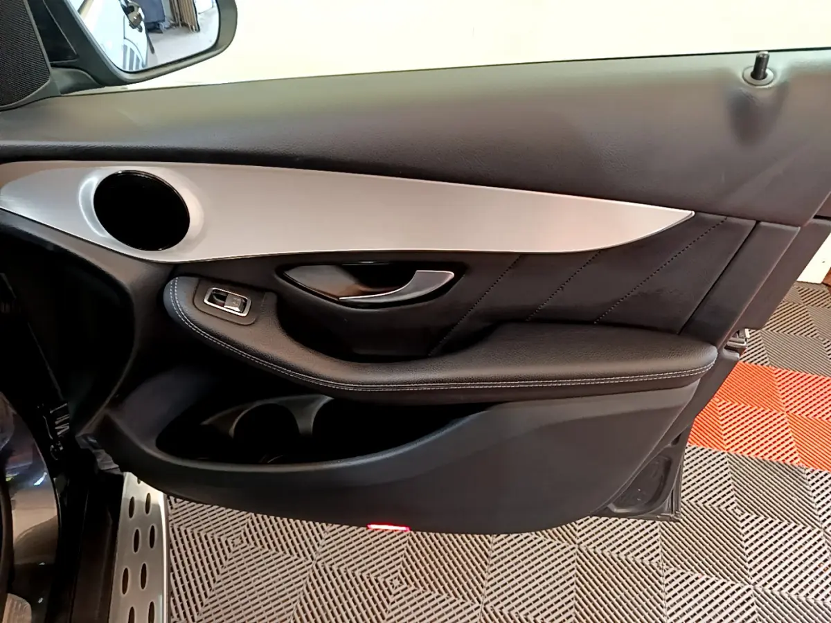 Vue rapprochée de la porte avant gauche gris foncé du Mercedes GLC 300 E AMG Line avec insert aluminium et commande de vitre.
