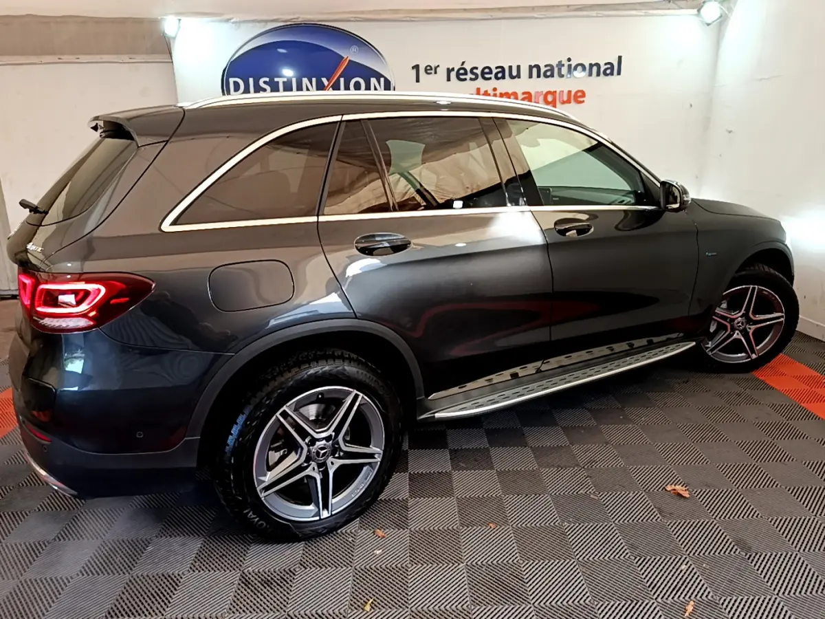 Vue de profil côté droit d'un Mercedes GLC 300 E AMG Line gris foncé avec jantes alliage et feux arrière allumés.