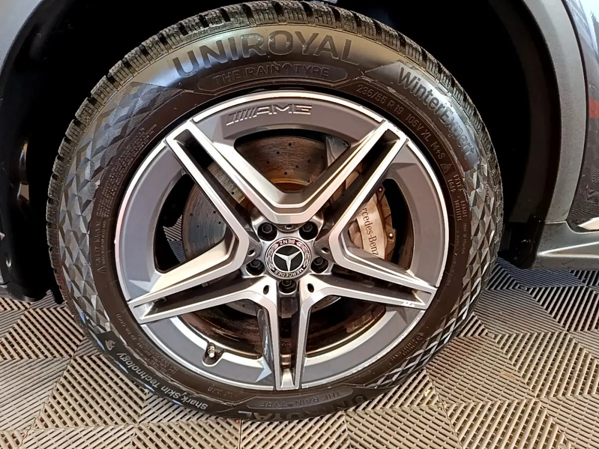 Gros plan sur la roue avant droite AMG du Mercedes GLC 300 E AMG Line gris foncé avec pneu Uniroyal hiver.